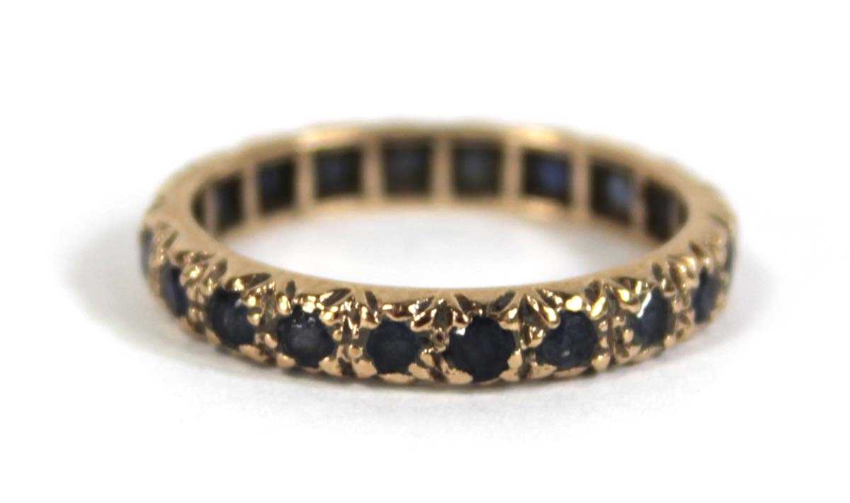 Lot 570 - A 9ct yellow gold eternity ring set sapphires,...
