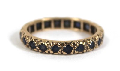 Lot 570 - A 9ct yellow gold eternity ring set sapphires,...
