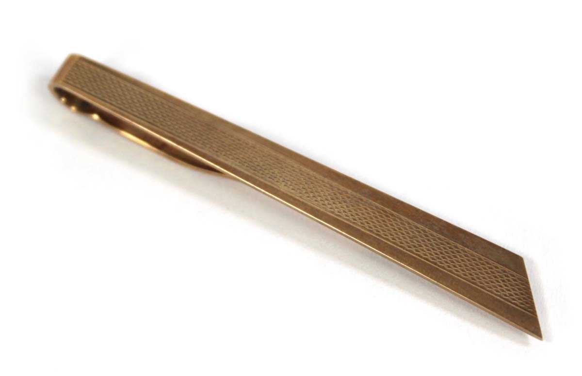 Lot 574 - A 9ct yellow gold engine turned tie clip,...
