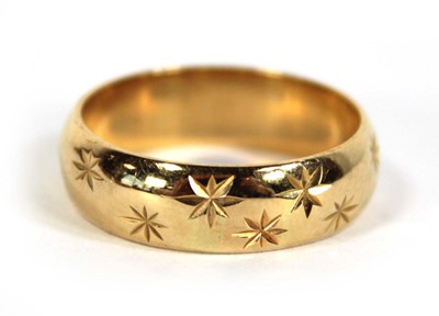 Lot 579 - An 18ct yellow gold star engraved wedding band,...