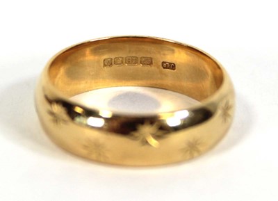 Lot 579 - An 18ct yellow gold star engraved wedding band,...