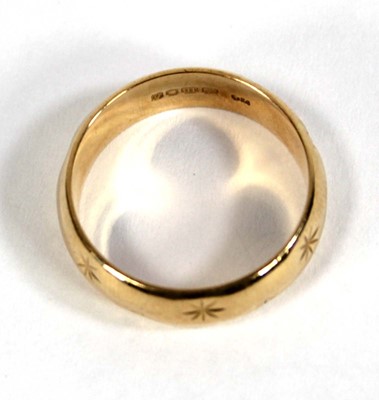 Lot 579 - An 18ct yellow gold star engraved wedding band,...
