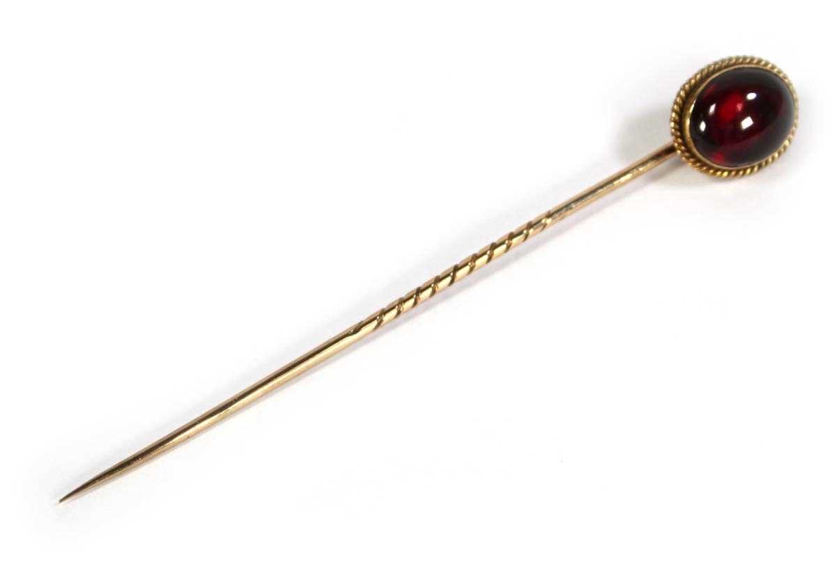 Lot 623 - A yellow metal stick pin set cabochon garnet...
