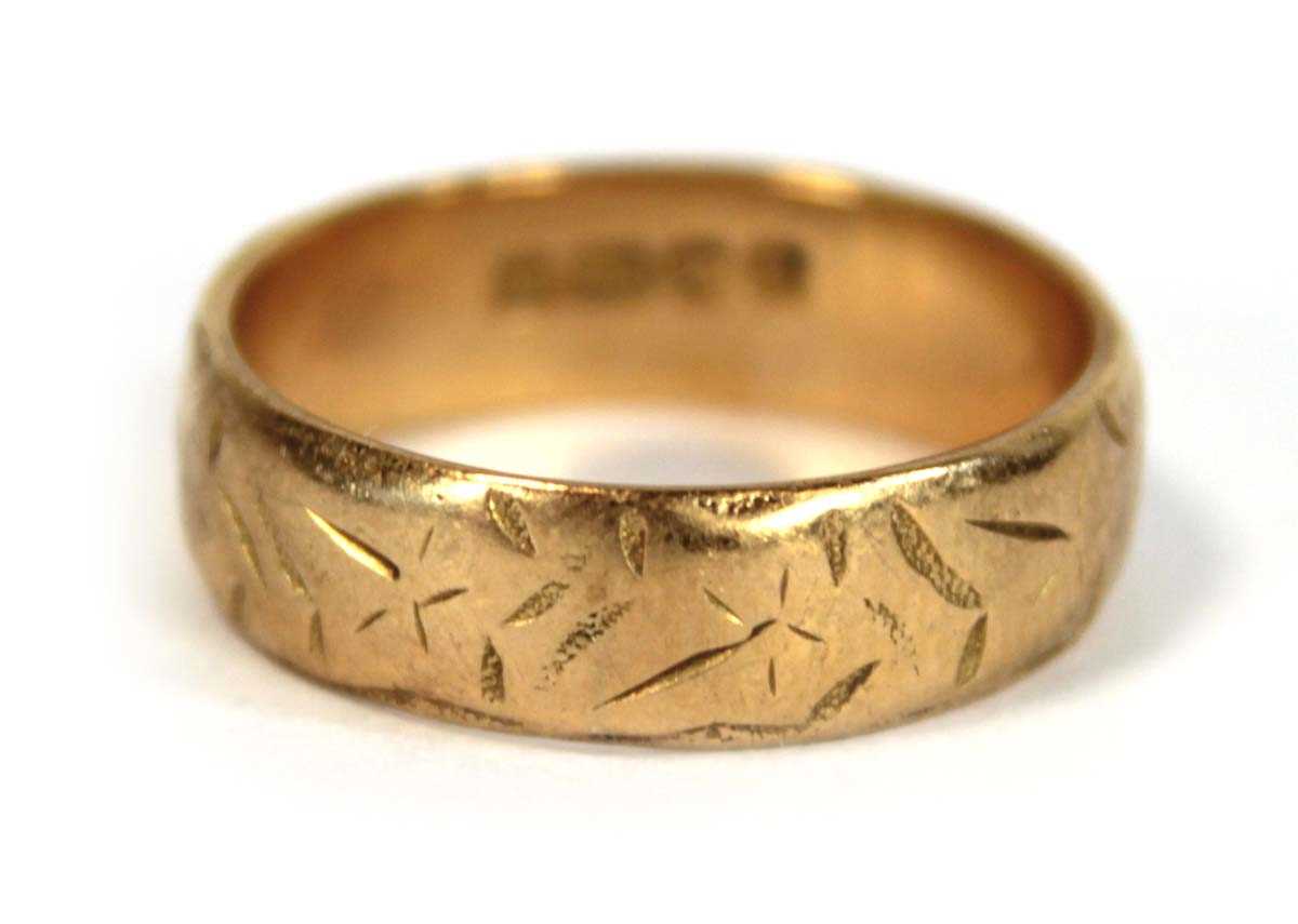 Lot 634 - An 18ct yellow gold engraved wedding band,...