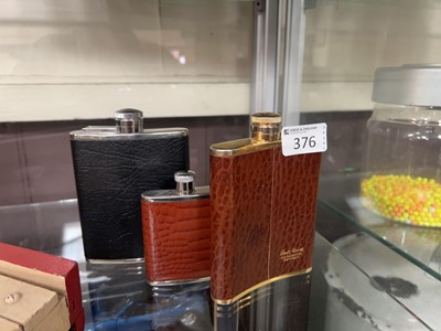 Lot 376 - A leather bound yellow metal hip flasks along...