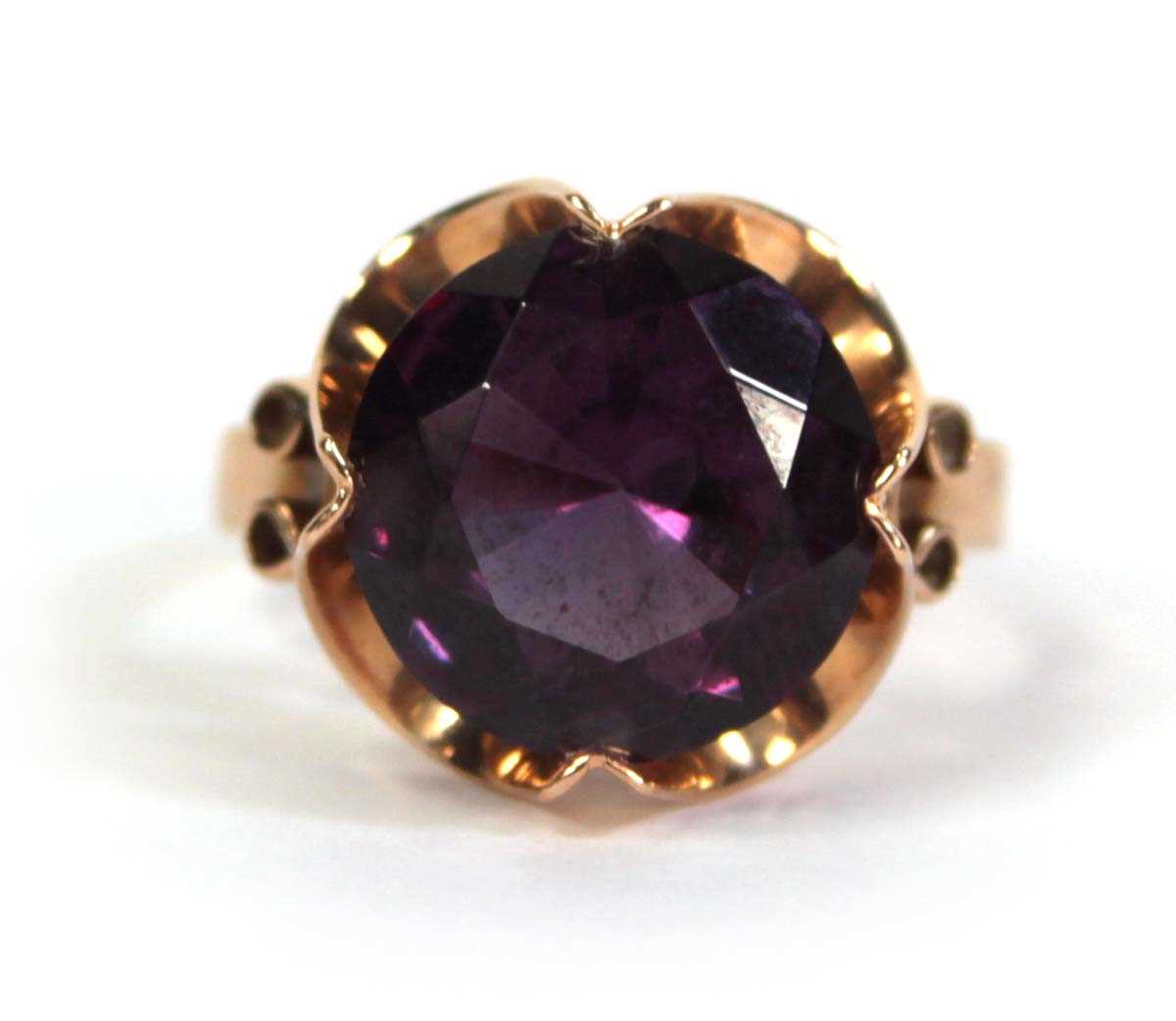 Lot 511 - A 14ct yellow gold ring set circular purple...